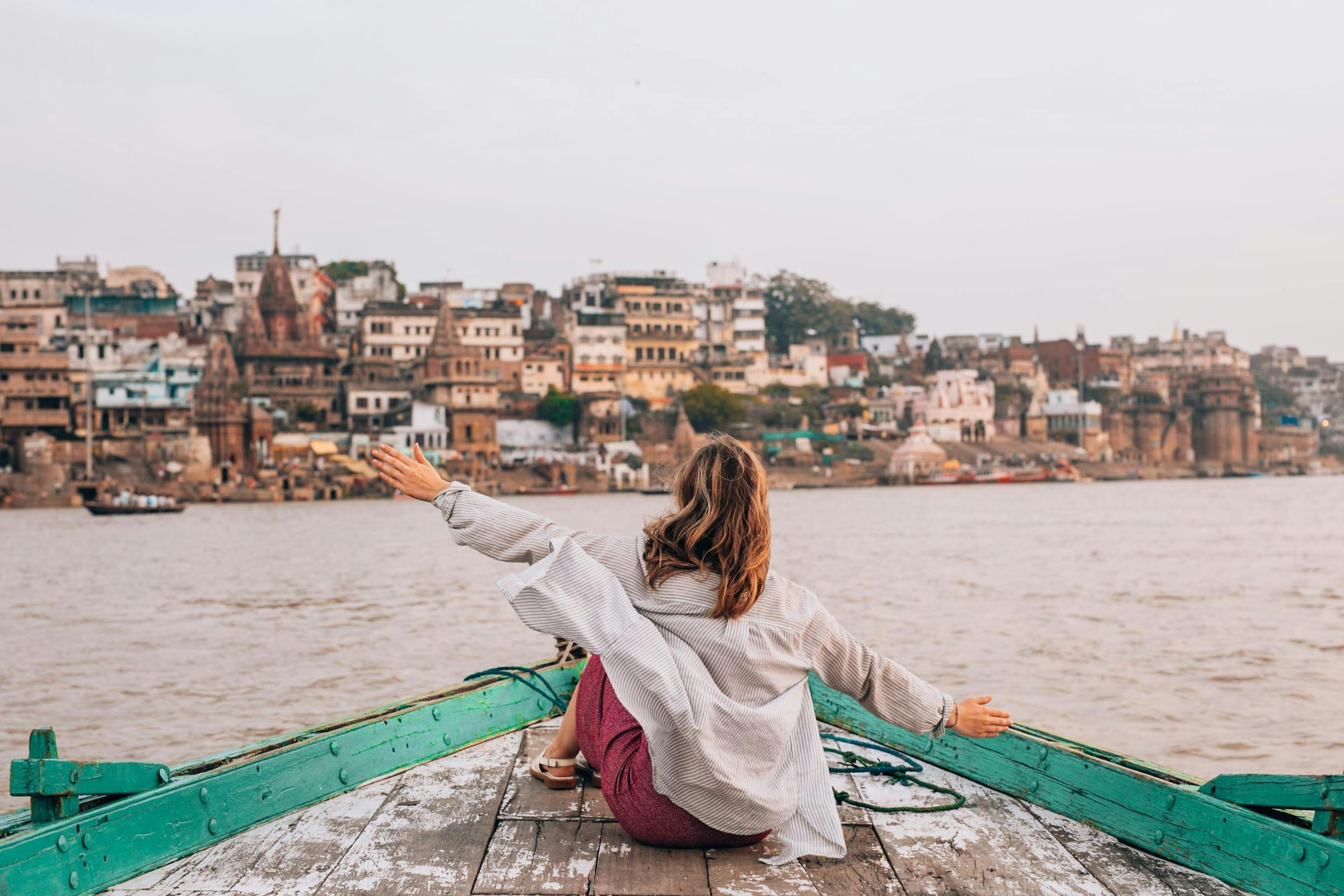 A guest on the prow of a boat at first light, the ghats behind